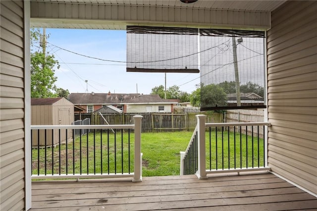 wooden terrace featuring a fenced backyard, a storage unit, an outbuilding, and a yard