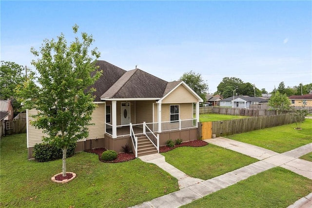 bungalow-style house with a porch, a front lawn, roof with shingles, and fence