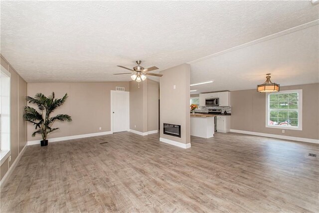 32536 D Wascom Rd, Mount Hermon, LA 70450 - unfurnished living room featuring light wood-style floors, a textured ceiling, ceiling fan, and baseboards