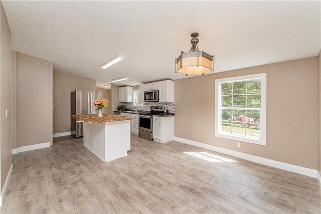 32536 D Wascom Rd, Mount Hermon, LA 70450 - kitchen featuring a kitchen island, light wood-type flooring, baseboards, stainless steel appliances, and white cabinetry