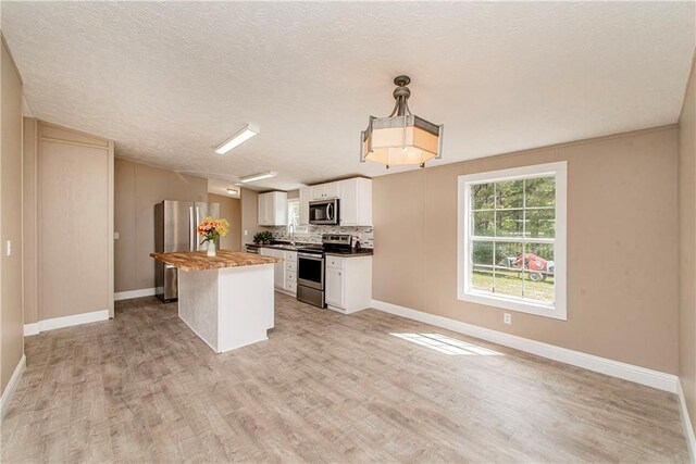 32536 D Wascom Rd, Mount Hermon, LA 70450 - kitchen featuring a kitchen island, baseboards, white cabinets, light wood-style floors, and stainless steel appliances
