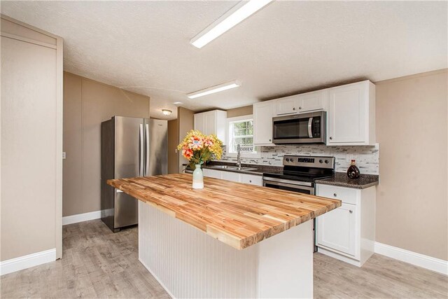 32536 D Wascom Rd, Mount Hermon, LA 70450 - kitchen featuring appliances with stainless steel finishes, white cabinets, decorative backsplash, and light wood-type flooring
