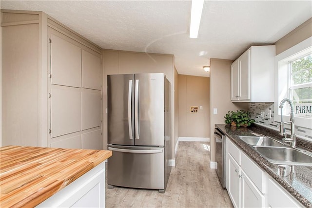 32536 D Wascom Rd, Mount Hermon, LA 70450 - kitchen with dishwasher, a sink, freestanding refrigerator, light wood-style floors, and white cabinetry