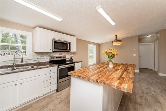 32536 D Wascom Rd, Mount Hermon, LA 70450 - kitchen featuring appliances with stainless steel finishes, a sink, light wood-style flooring, white cabinetry, and tasteful backsplash