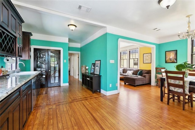 1818 Paul Morphy St, New Orleans, LA 70119 - kitchen with visible vents, stainless steel dishwasher, hardwood / wood-style flooring, a sink, and an inviting chandelier