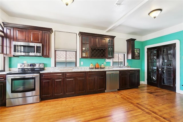 1818 Paul Morphy St, New Orleans, LA 70119 - kitchen with dark brown cabinets, a sink, glass insert cabinets, stainless steel appliances, and light wood-style flooring