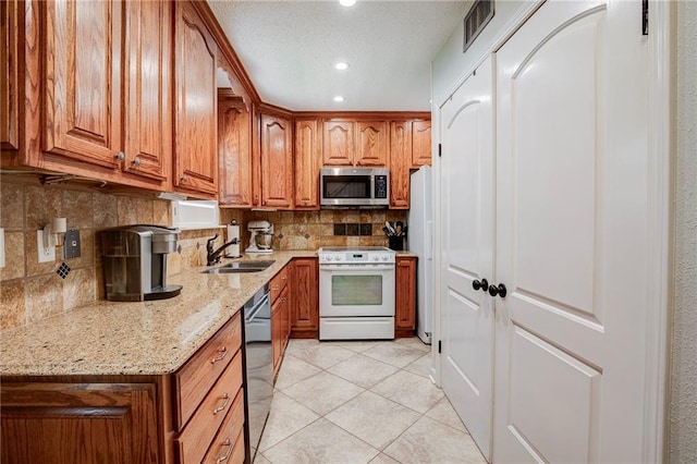 25 Brandon Hall Dr Unit A, Destrehan, LA 70047 - kitchen featuring a sink, brown cabinets, white appliances, and light stone counters