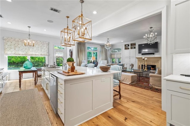 34 Riverdale Dr, Covington, LA 70433 - kitchen featuring a chandelier, crown molding, a warm lit fireplace, dishwasher, and light wood finished floors