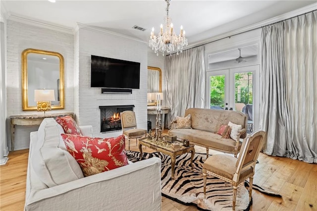 34 Riverdale Dr, Covington, LA 70433 - living area with a fireplace, light wood-style flooring, a chandelier, ornamental molding, and french doors