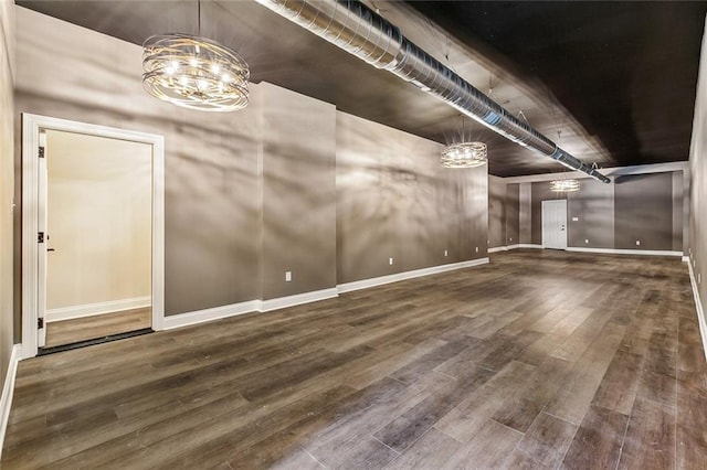 interior space with baseboards, a notable chandelier, and wood finished floors