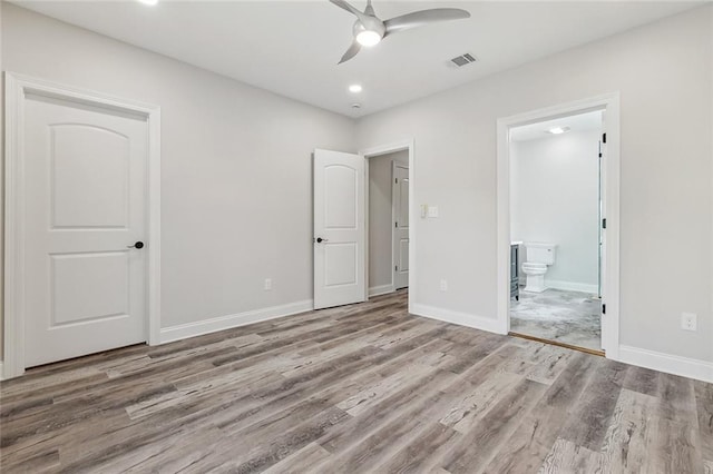 unfurnished bedroom featuring visible vents, wood finished floors, baseboards, recessed lighting, and ensuite bath