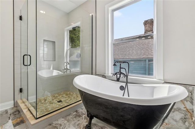 bathroom with marble finish floor, a freestanding tub, and a shower stall