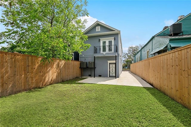 back of house featuring a balcony, a patio, a fenced backyard, french doors, and a yard