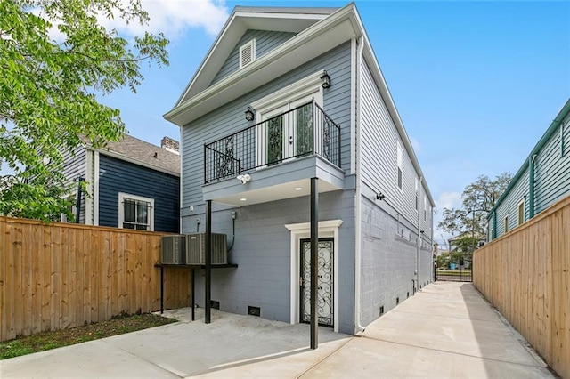 back of property featuring central AC unit, a patio area, fence, and a balcony