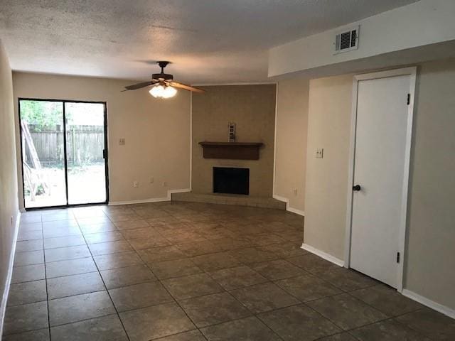 47 Birdie Dr Unit 7, Slidell, LA 70460 - unfurnished living room featuring dark tile patterned flooring, a fireplace with raised hearth, ceiling fan, and visible vents