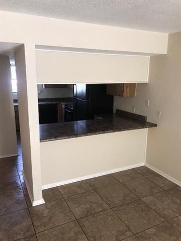 47 Birdie Dr Unit 7, Slidell, LA 70460 - kitchen with dark tile patterned floors, freestanding refrigerator, a textured ceiling, and dark countertops