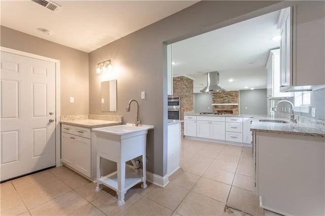 125 Vaccaro St, Independence, LA 70443 - kitchen with light tile patterned flooring, visible vents, a sink, wall chimney exhaust hood, and backsplash