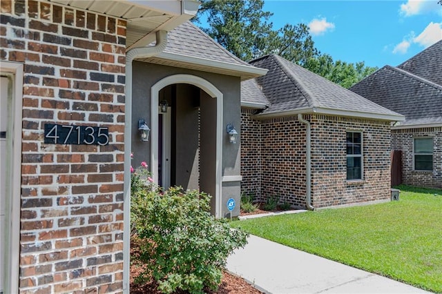 47135 Vineyard Trce, Hammond, LA 70401 - view of exterior entry featuring brick siding, a shingled roof, and a lawn