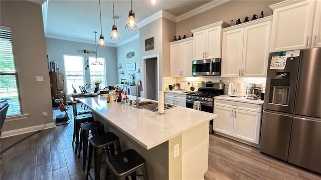 318 Saw Grass Loop, Covington, LA 70435 - kitchen featuring appliances with stainless steel finishes, dark wood-type flooring, an island with sink, ornamental molding, and a sink