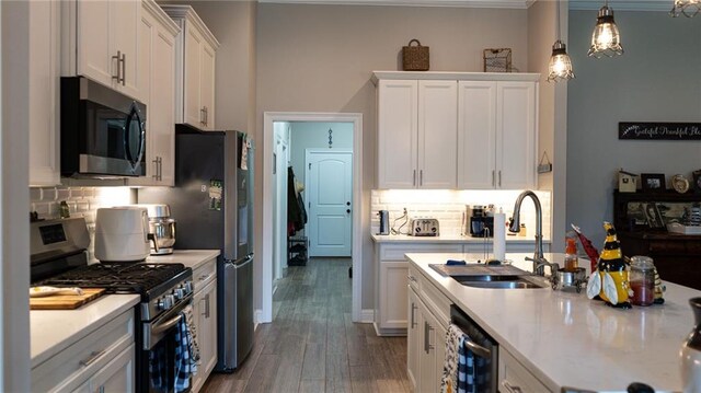 318 Saw Grass Loop, Covington, LA 70435 - kitchen featuring appliances with stainless steel finishes, a sink, white cabinetry, backsplash, and wood finished floors