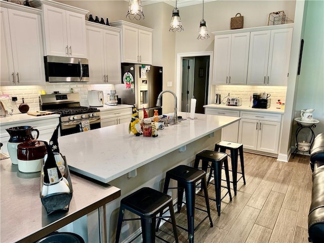 318 Saw Grass Loop, Covington, LA 70435 - kitchen featuring appliances with stainless steel finishes, backsplash, crown molding, white cabinets, and a breakfast bar