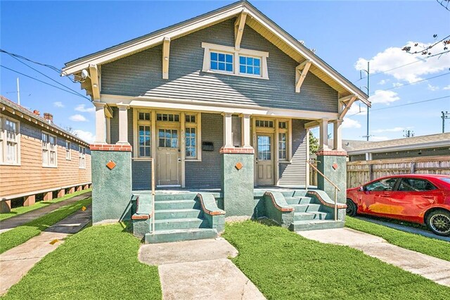 view of front of property featuring covered porch, fence, and a front yard
