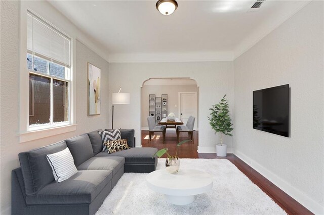 living area with arched walkways, baseboards, dark wood finished floors, and visible vents