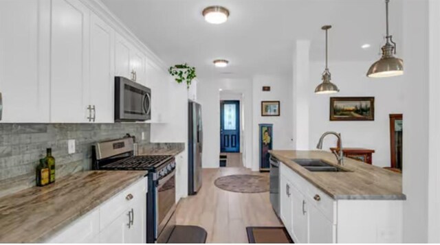 542 Abalon Ct, New Orleans, LA 70114 - kitchen featuring appliances with stainless steel finishes, a sink, white cabinetry, tasteful backsplash, and light wood finished floors