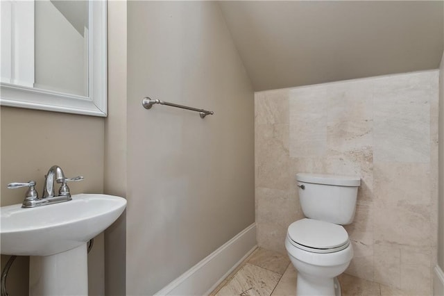 400 40th St, New Orleans, LA 70124 - bathroom featuring toilet, vaulted ceiling, a sink, and tile walls