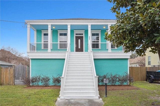 view of front of home featuring fence, stairs, a front lawn, and covered porch