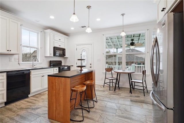 kitchen with a sink, white cabinetry, black appliances, and a healthy amount of sunlight