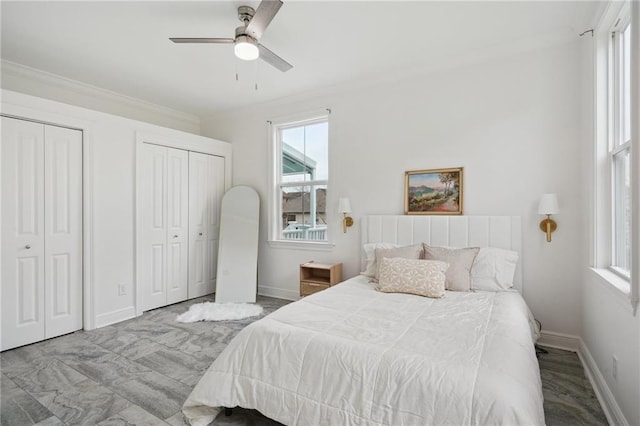 bedroom featuring two closets, crown molding, multiple windows, and baseboards