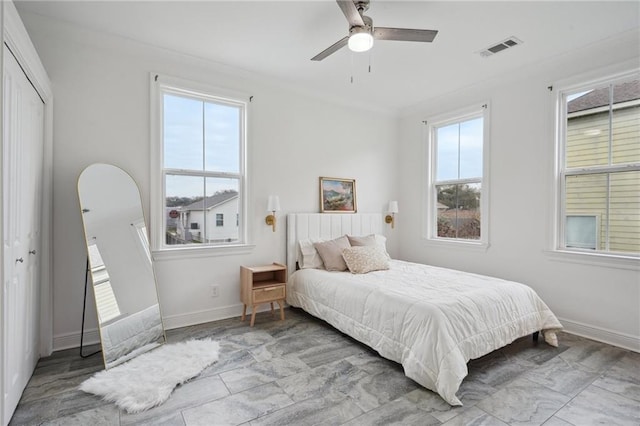 bedroom with ceiling fan, baseboards, visible vents, ornamental molding, and a closet