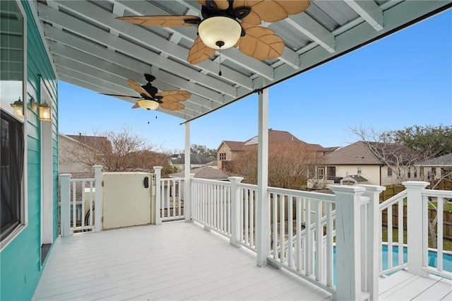 deck featuring a residential view, a fenced in pool, and a ceiling fan