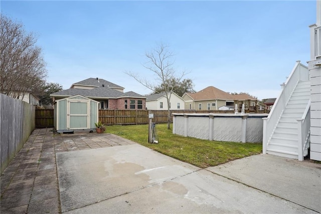 view of patio featuring stairs, a storage shed, a fenced in pool, a fenced backyard, and an outbuilding