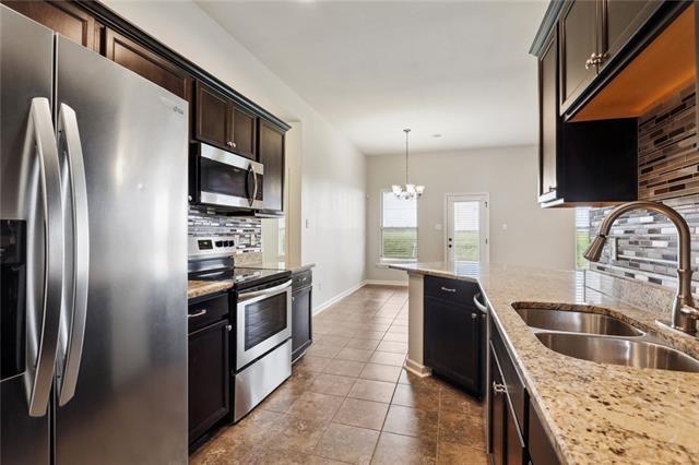 324 Ashton Oaks Ln, Luling, LA 70070 - kitchen with appliances with stainless steel finishes, a sink, tasteful backsplash, a chandelier, and light stone counters