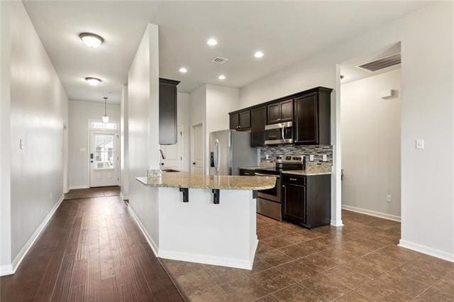 324 Ashton Oaks Ln, Luling, LA 70070 - kitchen featuring stainless steel appliances, a breakfast bar area, a peninsula, dark brown cabinets, and backsplash