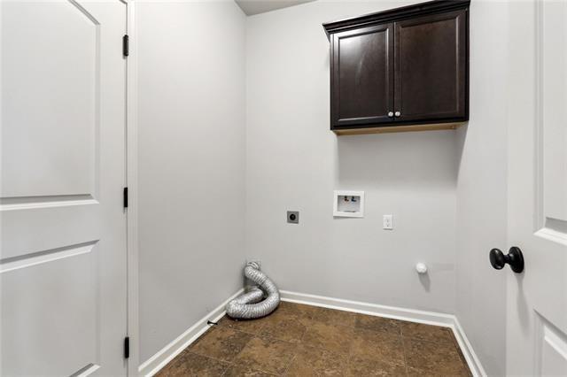 324 Ashton Oaks Ln, Luling, LA 70070 - laundry area featuring electric dryer hookup, washer hookup, baseboards, cabinet space, and stone finish floors