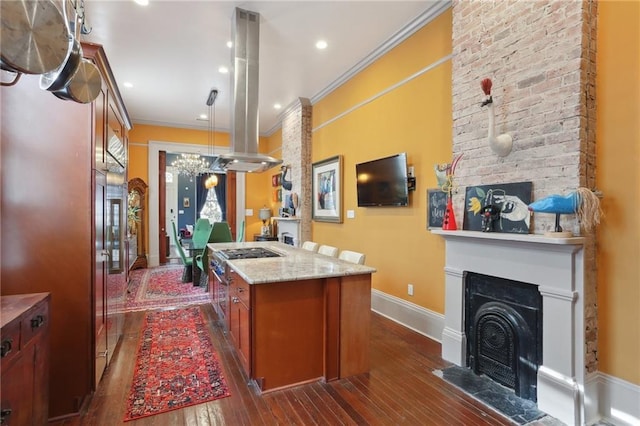 1907 N Rampart St, New Orleans, LA 70116 - kitchen featuring brown cabinetry, island range hood, a center island with sink, dark wood-type flooring, and a large fireplace