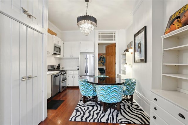 1907 N Rampart St, New Orleans, LA 70116 - kitchen with white cabinetry, crown molding, an inviting chandelier, and appliances with stainless steel finishes