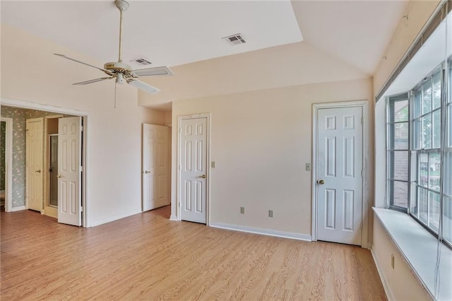 unfurnished bedroom with visible vents, multiple closets, lofted ceiling, baseboards, and light wood-style flooring