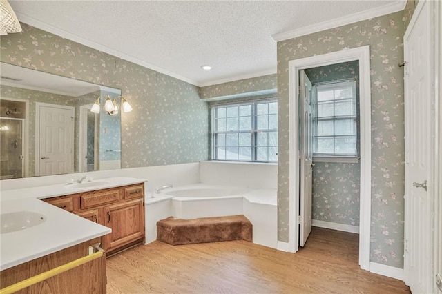 bathroom featuring a garden tub, wood finished floors, vanity, ornamental molding, and wallpapered walls