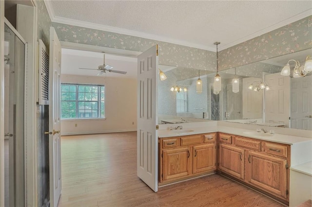 full bathroom with crown molding, a sink, a textured ceiling, and wood finished floors