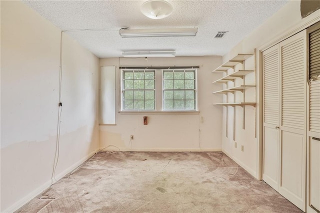 unfurnished bedroom featuring light carpet, a textured ceiling, baseboards, visible vents, and a closet