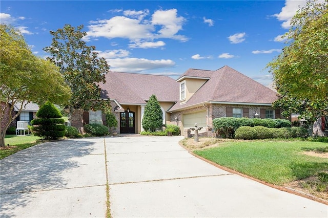 single story home featuring a shingled roof, an attached garage, a front lawn, brick siding, and driveway