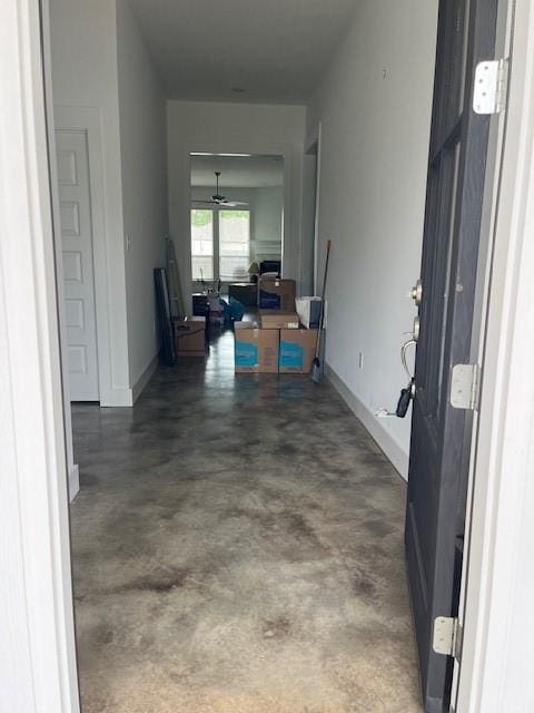 hallway with baseboards and concrete floors