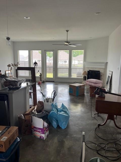 misc room with a ceiling fan, finished concrete floors, and a fireplace