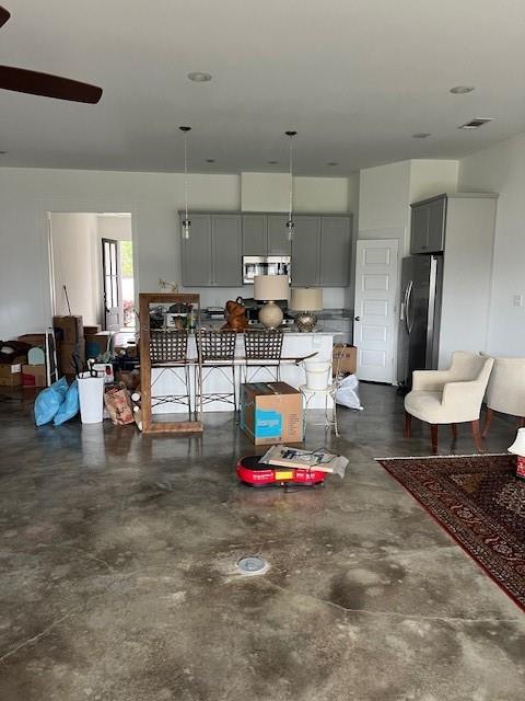 living room featuring visible vents, concrete floors, and ceiling fan