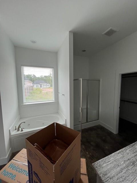 bathroom with a whirlpool tub, baseboards, a shower stall, and wood finished floors