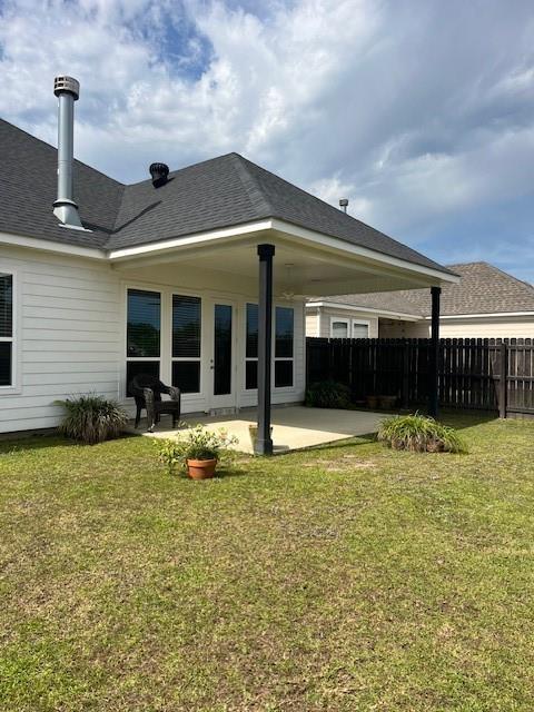 rear view of property featuring a lawn, fence, and a patio area